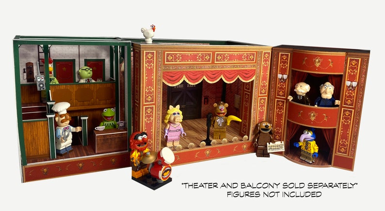 May include: A three-section cardboard playset depicting a Muppet theater stage with a red curtain, a balcony, and a backstage area. The set is decorated with gold trim and features a variety of Muppet characters, including Miss Piggy, Fozzie Bear, Animal, and Gonzo. The text "THEATER AND BALCONY SOLD SEPARATELY FIGURES NOT INCLUDED" is printed at the bottom of the image.