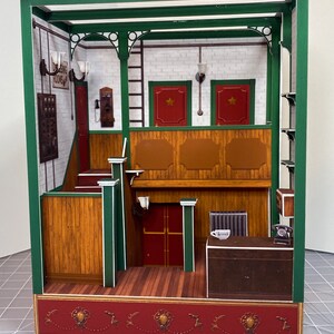 May include: A miniature paper model of a building interior with a wooden counter, a red door, and a sign that reads "Dining Rooms".