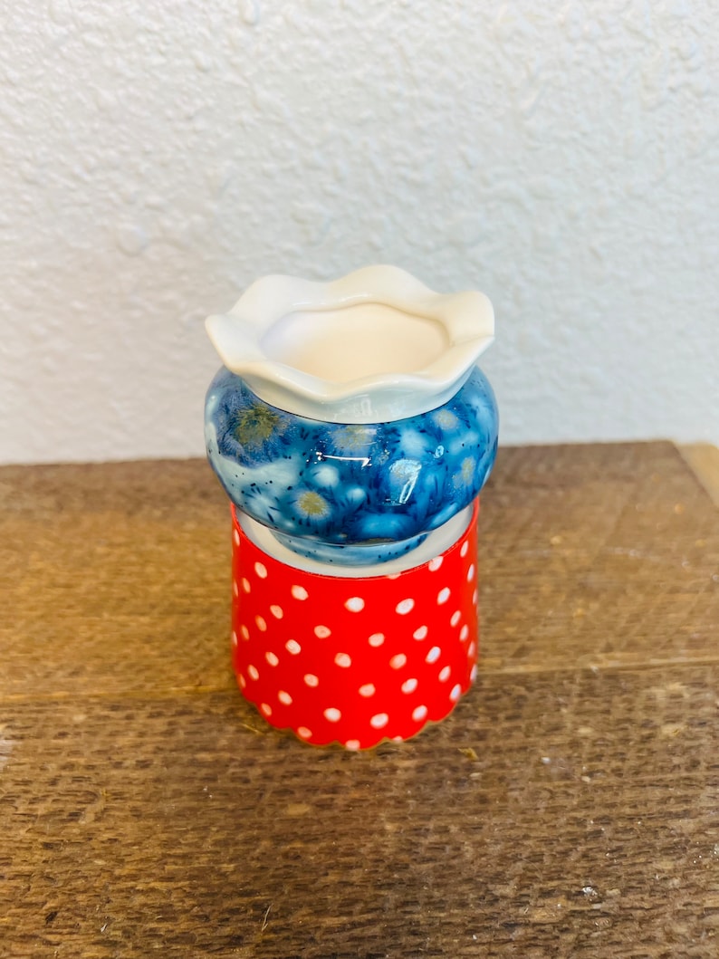 May include: A small, blue and white ceramic planter with a white rim and a red polka dot base.