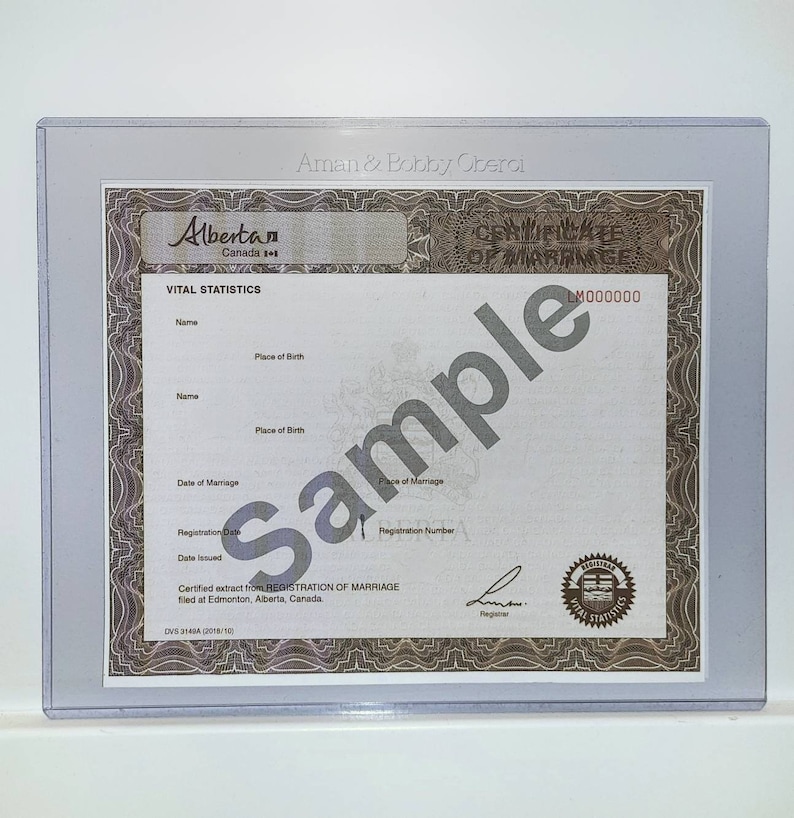 May include: A white certificate of marriage from Alberta, Canada. The certificate has a brown border and the text "Certificate of Marriage" and "LM000000" printed in brown. The text "Vital Statistics" is printed in black at the top of the certificate.