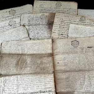 Peut inclure: Ensemble de documents manuscrits anciens, probablement des lettres ou manuscrits historiques. Le papier jauni présente une encre estompée et des sceaux décoratifs. L'écriture est cursive, suggérant une origine ancienne.