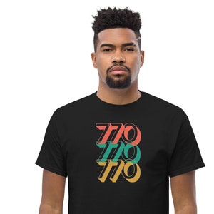 May include: A black t-shirt with a graphic design of the number 770 repeated three times in different colors: red, green, and yellow.