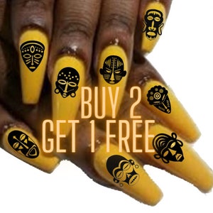 May include: A set of black and white African tribal mask nail decals on yellow nail polish. The image includes the text "BUY 2 GET 1 FREE".