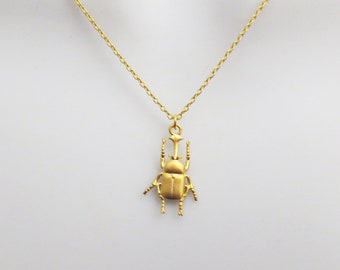 Op de afbeelding: Een gouden ketting met een gouden kever hanger.