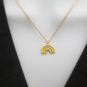 May include: A gold chain necklace with a gold rainbow pendant.
