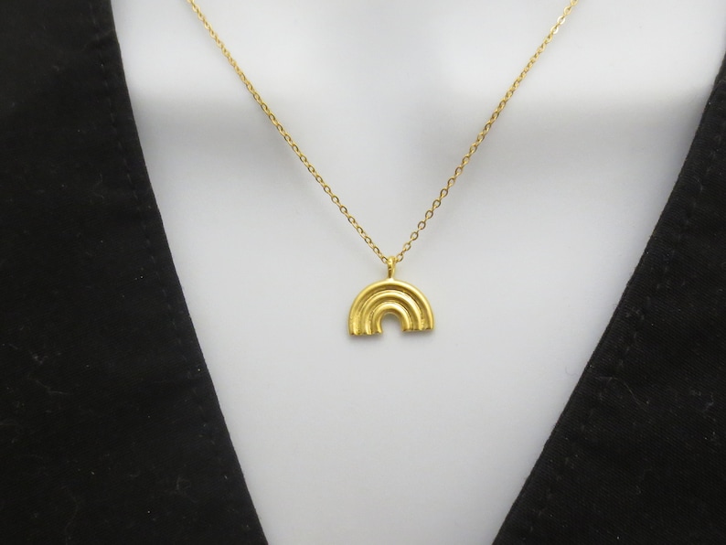 May include: A gold chain necklace with a gold rainbow pendant.