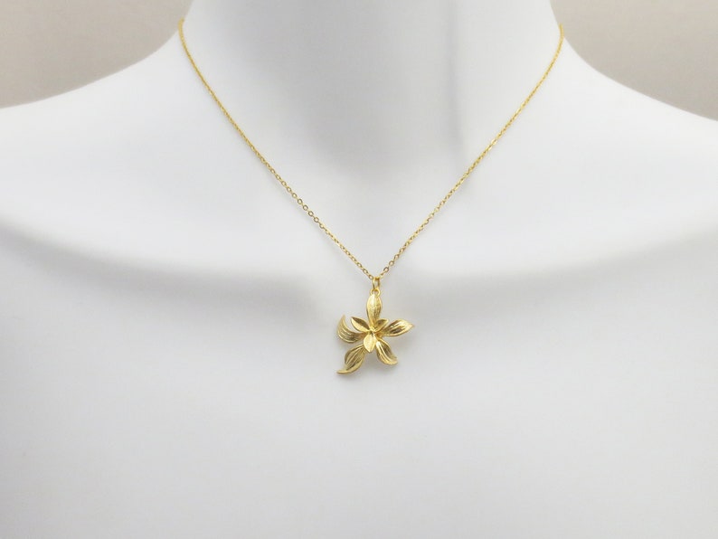 May include: A gold chain necklace with a delicate flower pendant. The flower is made of gold and has a detailed design.