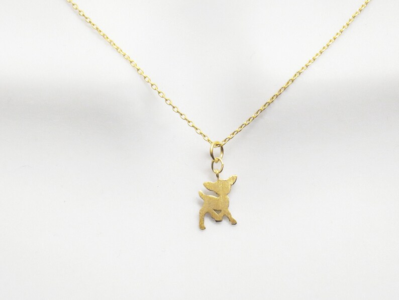 May include: A gold chain necklace with a delicate deer pendant. The deer is a simple silhouette with a smooth, polished finish.