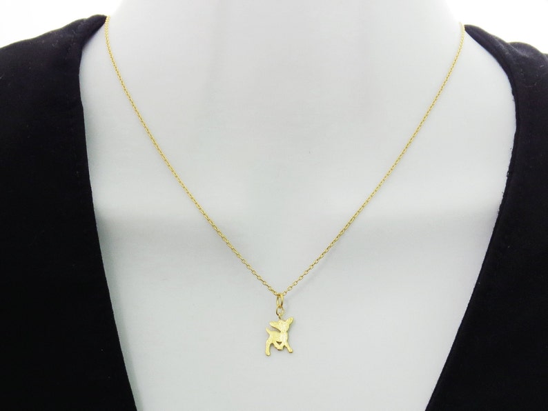 May include: A gold chain necklace with a small gold deer pendant.