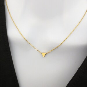 Puede incluir: Un collar de cadena dorada con un peque&ntilde;o colgante triangular.