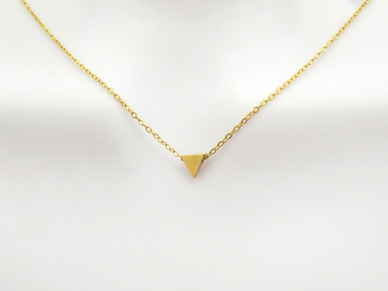 Puede incluir: Un collar de cadena de oro con un peque&ntilde;o colgante triangular de oro.