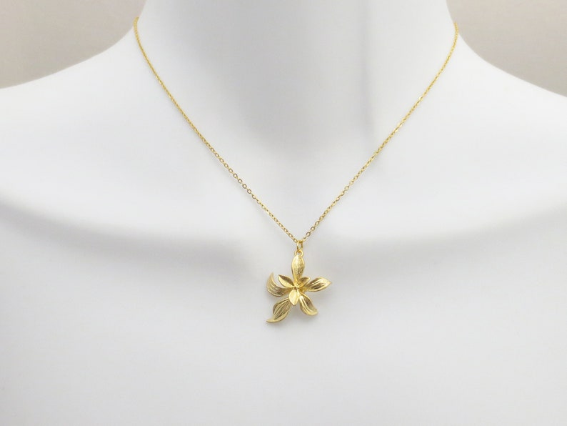 May include: A gold chain necklace with a delicate flower pendant. The flower is made of gold and has a textured surface.