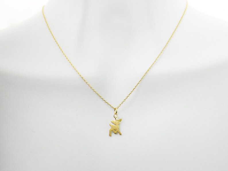 May include: A gold chain necklace with a small deer pendant.