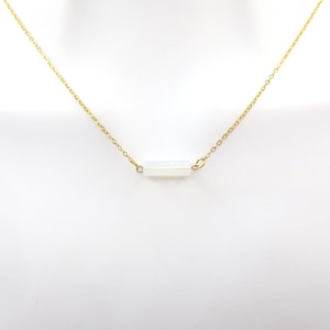 Könnte beinhalten: Eine zarte goldene Kettenkette mit einem einzigen weißen Opal-Bar-Anhänger.