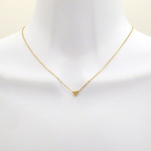 Puede incluir: Un collar de cadena dorada con un peque&ntilde;o colgante triangular.