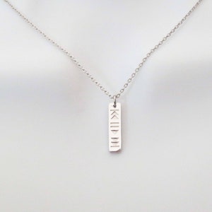 May include: A silver necklace with a pendant featuring Roman numerals engraved on it.