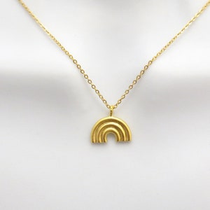 May include: A gold chain necklace with a rainbow pendant. The pendant is made of multiple layers of gold metal.