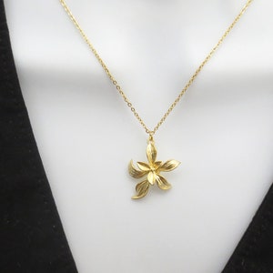 May include: A gold chain necklace with a delicate gold flower pendant.