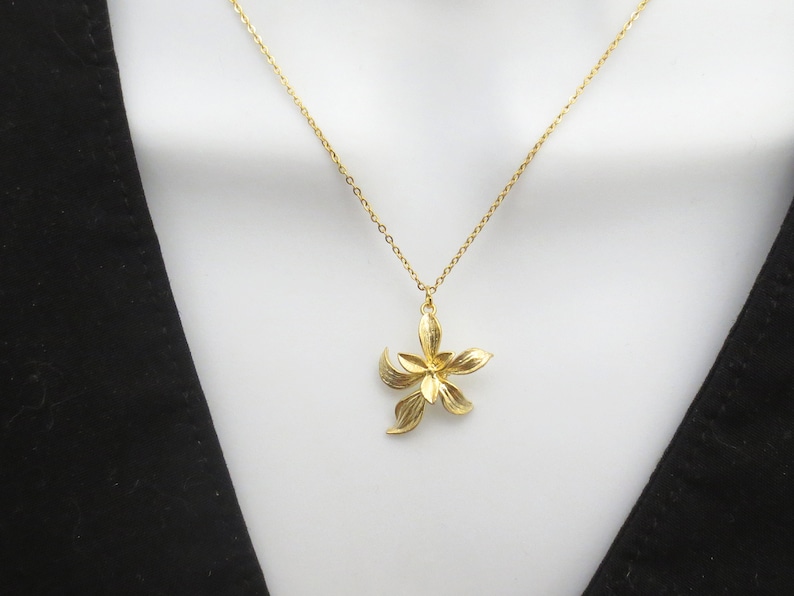 May include: A gold chain necklace with a delicate gold flower pendant.