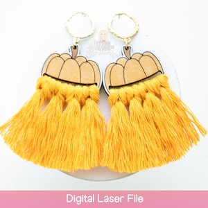 Op de afbeelding: Een paar pompoenvormige oorbellen met gele kwastjes. De oorbellen zijn gemaakt van hout en hebben een gouden metalen ring.