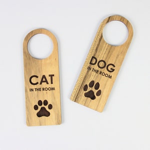 Peut inclure: Deux porte-manteaux en bois avec des empreintes de pattes et le texte "CAT IN THE ROOM" et "DOG IN THE ROOM".