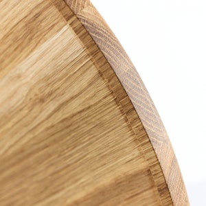 Close-up of a round oak wood serving tray showing natural wood grain patterns and smooth finish.