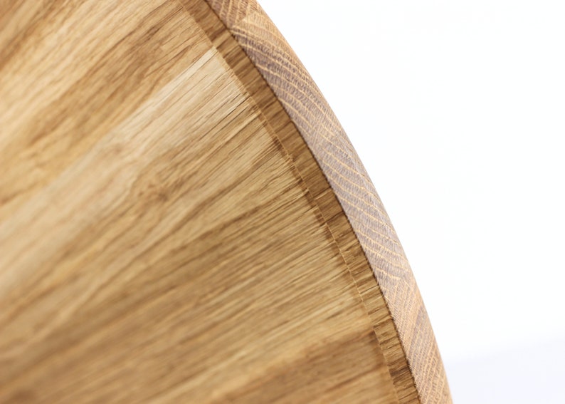 Close-up of a round oak wood serving tray showing natural wood grain patterns and smooth finish.