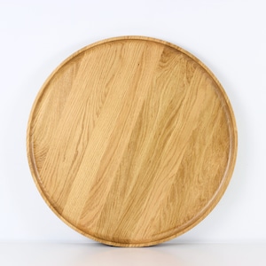 Handcrafted round oak serving tray with raised edge, displayed on a white surface.