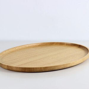 Handcrafted oval serving tray made from premium oak wood, featuring a smooth finish and natural wood grain. Perfect as a large ottoman tray, charcuterie board, or tea serving tray for home decor and entertaining
