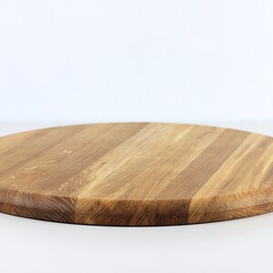 Round oak wood serving tray turned upside down, displaying the smooth bottom surface and natural wood grain.
