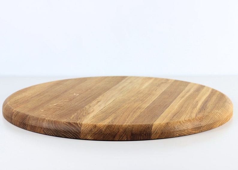 Round oak wood serving tray turned upside down, displaying the smooth bottom surface and natural wood grain.