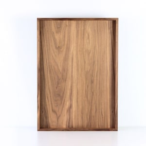 Puede incluir: Una bandeja rectangular de madera con un acabado de madera natural. La bandeja tiene un dise&ntilde;o simple y moderno y es perfecta para servir comida o bebidas.