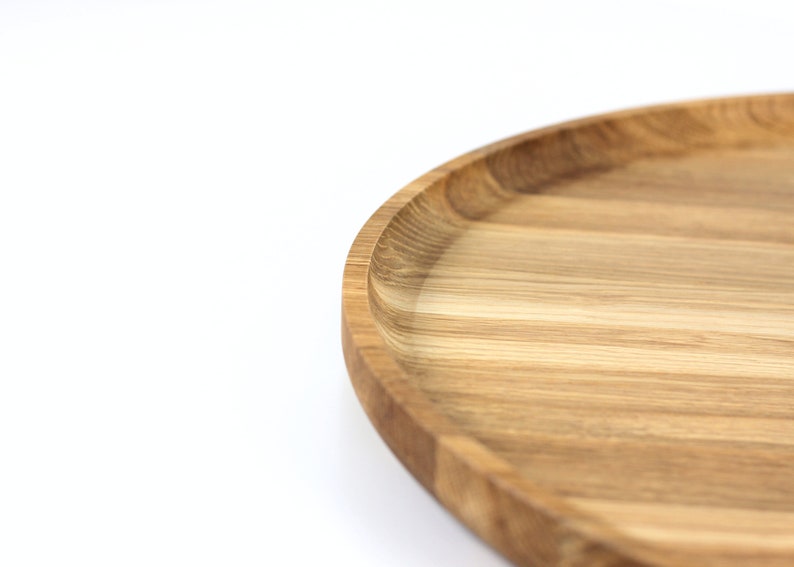 Close-up of a round oak wood serving tray showing natural wood grain patterns and smooth finish.
