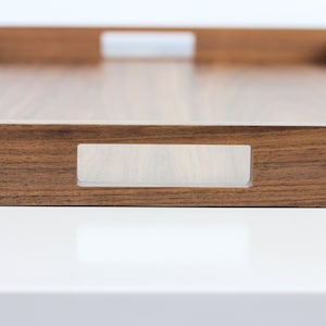 Puede incluir: Una bandeja de servir de madera con un acabado de madera natural y asas de acr&iacute;lico transparente. La bandeja tiene una forma rectangular y es perfecta para servir comida o bebidas.
