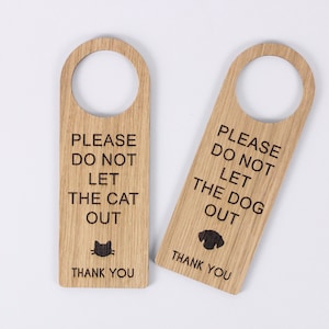 Könnte beinhalten: Zwei Holztürhänger mit dem Text "Bitte lass die Katze nicht raus" und "Bitte lass den Hund nicht raus". Jeder Hänger hat eine kleine Silhouette des Tieres und den Text "Danke".