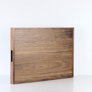 Puede incluir: Una bandeja rectangular de madera con un acabado de madera natural. La bandeja tiene un dise&ntilde;o sencillo con un borde ligeramente elevado.