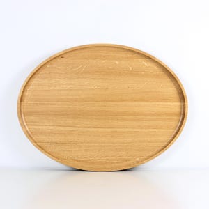 Handcrafted oval serving tray made from premium oak wood, featuring a smooth finish and natural wood grain. Perfect as a large ottoman tray, charcuterie board, or tea serving tray for home decor and entertaining