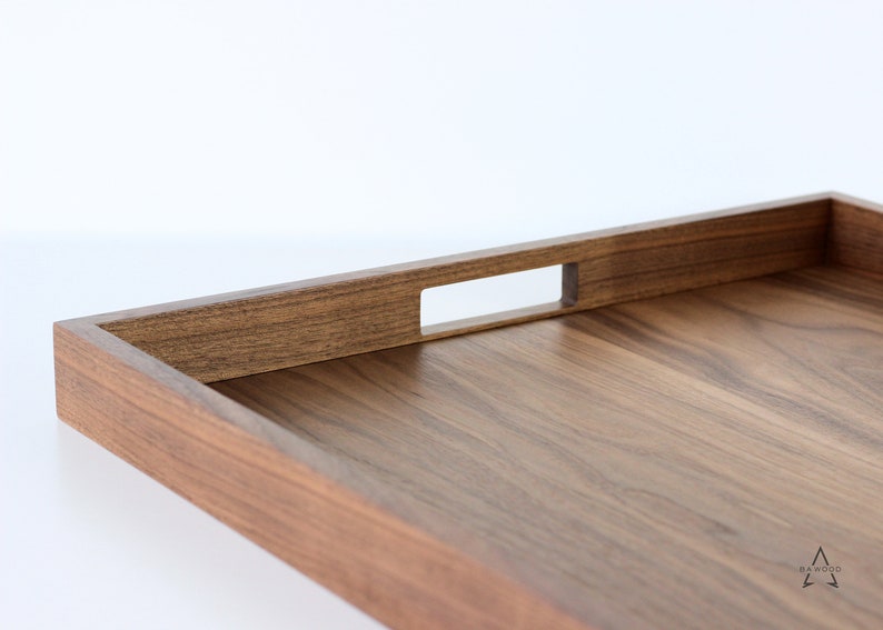 Puede incluir: Una bandeja rectangular de madera con acabado en nogal marr&oacute;n. La bandeja tiene un asa integrada con un recorte rectangular.