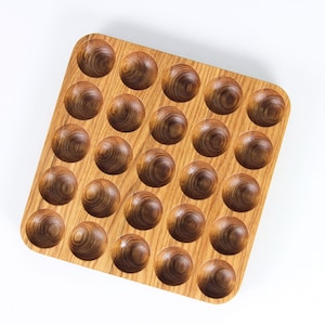Könnte beinhalten: Ein Holztablett mit 36 runden Vertiefungen. Das Tablett ist aus hellbraunem Holz mit natürlicher Maserung.