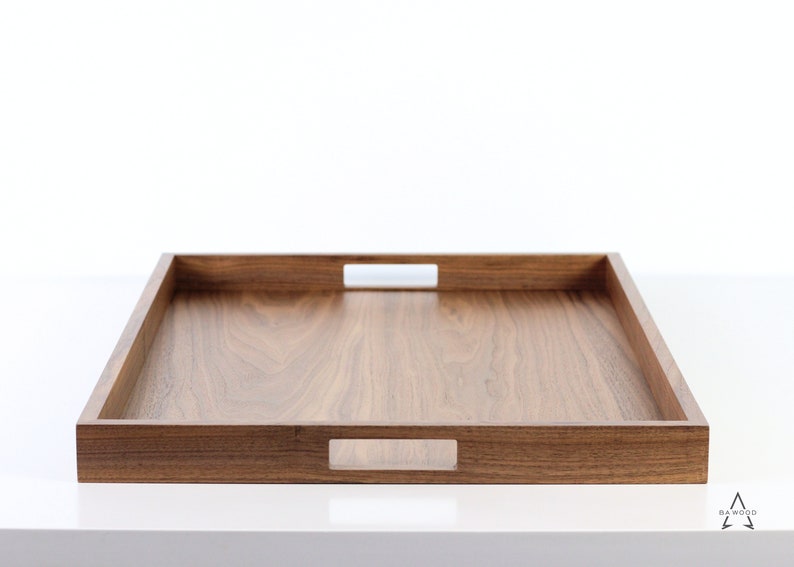 Puede incluir: Una bandeja rectangular de madera para servir con dos asas recortadas a cada lado. La bandeja est&aacute; hecha de madera de nogal y tiene un acabado natural.
