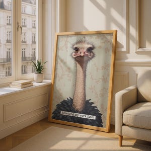 May include: A framed vertical wall art print featuring a detailed illustration of an ostrich with a serious expression. The ostrich has a long neck and dark feathers, set against a light beige background with a subtle floral pattern and the text Resetting my work face!