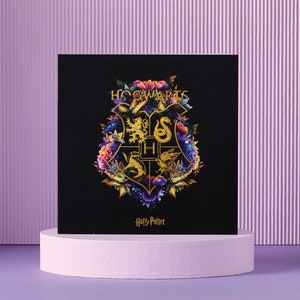 May include: A black square with the Hogwarts crest, adorned with vibrant flowers. The crest showcases a lion, snake, eagle, and badger, with the words "Hogwarts" and "Harry Potter" beneath the emblem.