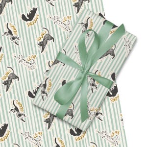 Puede incluir: Papel de regalo con un diseño de gato juguetón. El papel de regalo tiene un fondo a rayas verdes claras y blancas con ilustraciones de gatos en varias poses, con frases como "Purrrr" y "Snoooze". Una cinta verde claro está atada alrededor del regalo envuelto.