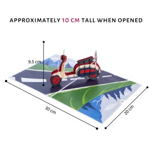 Puede incluir: Una tarjeta pop-up 3D roja y blanca con un scooter conduciendo por una carretera con monta&ntilde;as en el fondo. La tarjeta mide aproximadamente 10 cm de alto cuando est&aacute; abierta, 30 cm de ancho y 20 cm de profundidad.