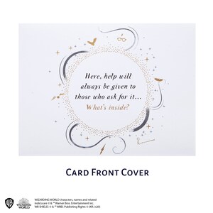 May include: A white rectangular greeting card featuring gold and grey decorative elements including stars, a bird, glasses, and a lightning bolt. The text reads: Here, help will always be given to those who ask for it... What's inside?