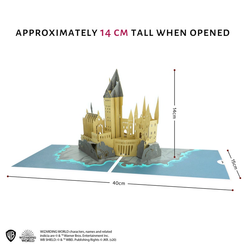 May include: A tan paper pop-up castle model featuring multiple towers and spires, set on a blue base with rocky details. The structure measures 14 cm tall when opened, with a total base width of 40 cm and a depth of 15 cm, including Wizarding World text.