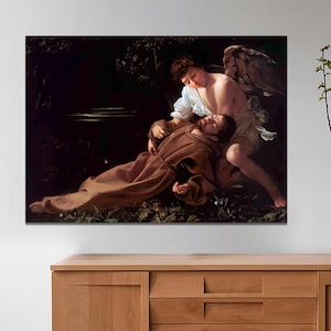May include: A painting depicting a scene of a man lying on the ground with an angel kneeling beside him. The angel has wings and is wearing a white robe. The man is wearing a brown robe and has a halo above his head. The background is dark and shadowy.