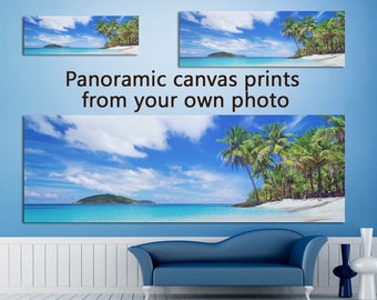 May include: A panoramic canvas print of a tropical beach scene with palm trees, white sand, and turquoise water. The print is displayed on a wall above a blue sofa.