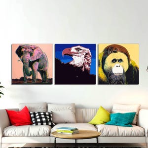 May include: Three colorful pop art prints featuring an elephant, a bald eagle, and an orangutan. The elephant is pink and gray, the eagle is white and black, and the orangutan is yellow and brown.
