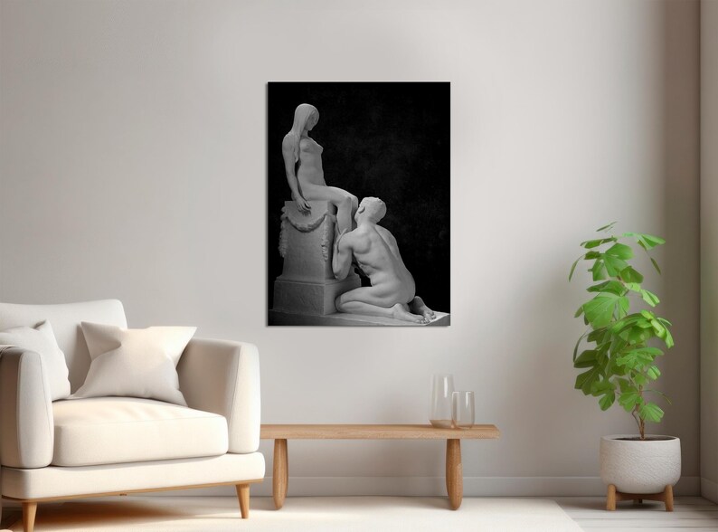 May include: Black and white photograph of two statues, one sitting on a pedestal and the other kneeling. The statues are in a romantic pose, with the kneeling statue looking up at the seated statue.